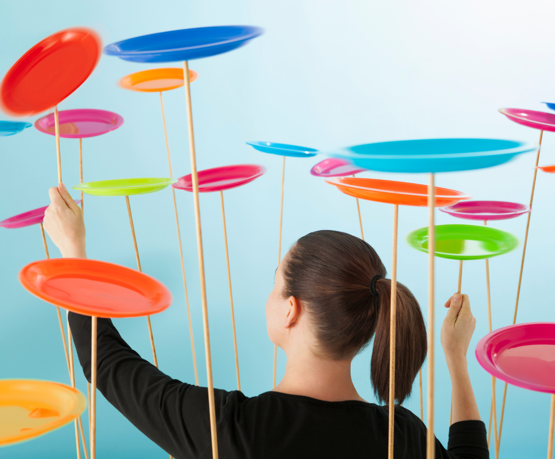 Woman balancing multiple spinning plates – symbol of juggling tasks as a creative entrepreneur