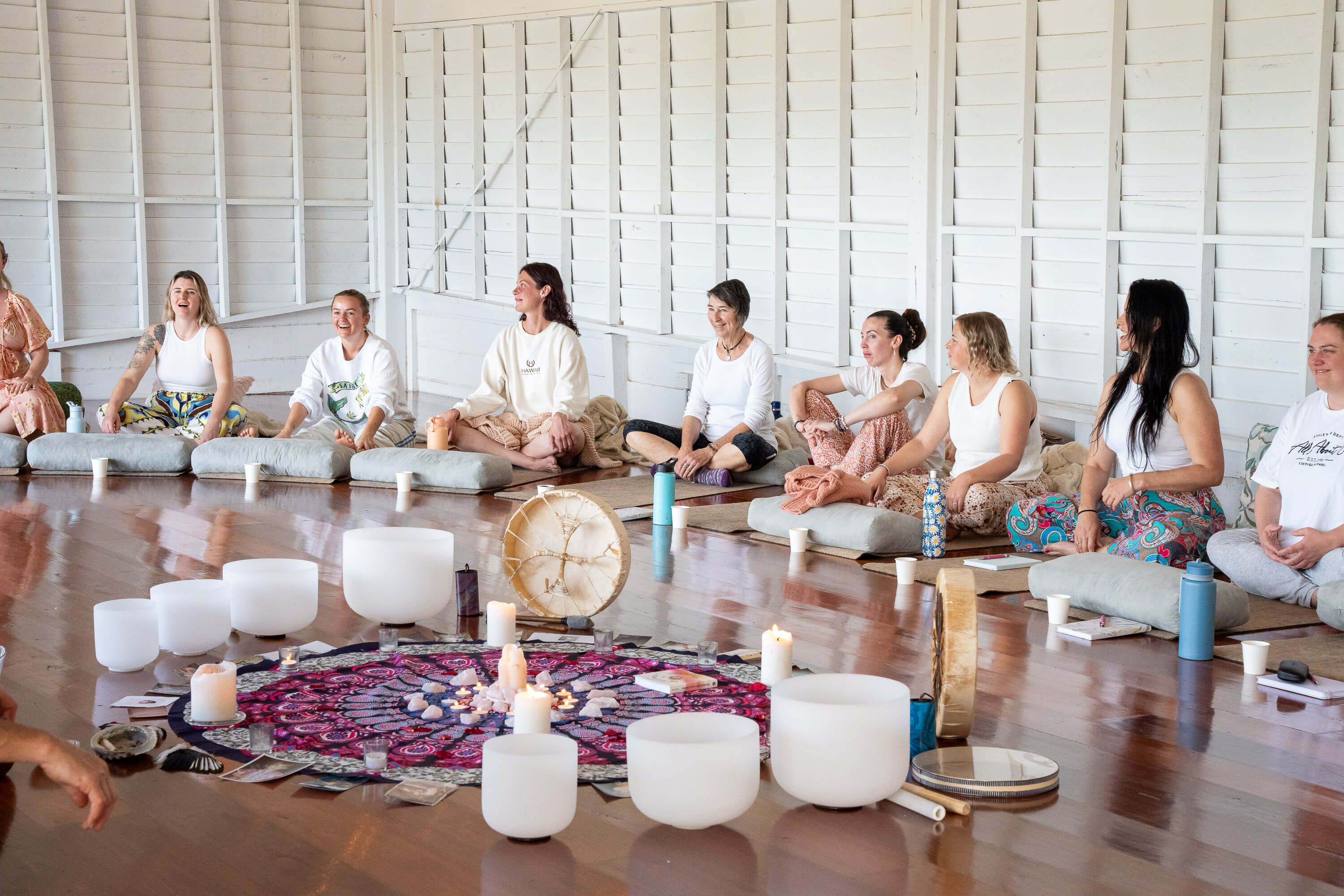Women gathering in circle with singing bowls and crystals