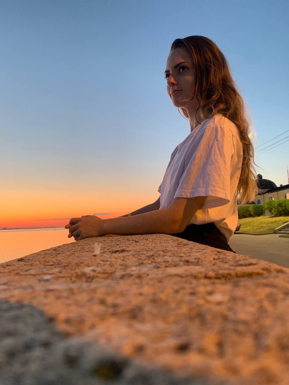Девушка сидит на берегу во время заката, глядя вдаль — символ внутреннего спокойствия, достигнутого через практику селф-коучинга и осознанной работы с эмоциями