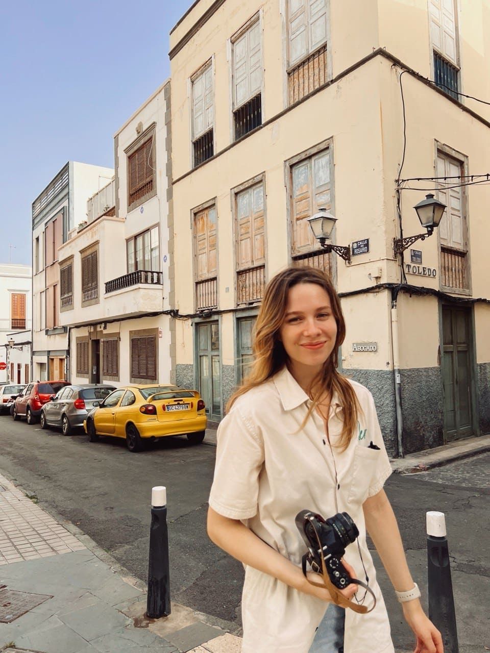 Лиза стоит на солнечной улице с камерой в руках, улыбается — её путь в коучинговой программе помог ей обрести внутреннюю опору и уверенность в себе.