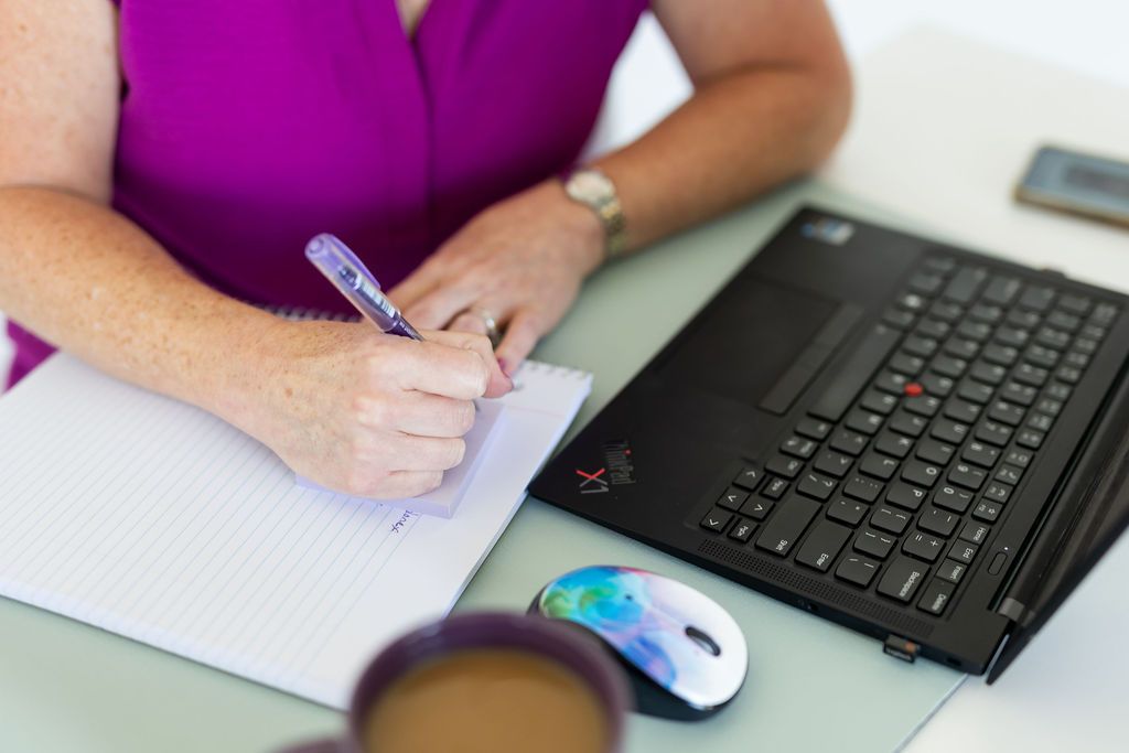 Owner in pink shirt standing behind desk
