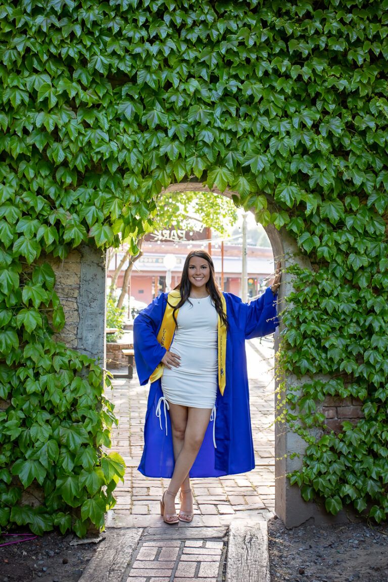 Teenage girl in graduation attire posing confidently on a downtown street in Grass Valley, CA.