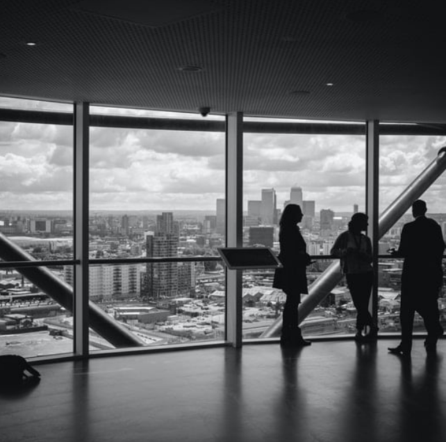 People looking out over cityscape through large windows.