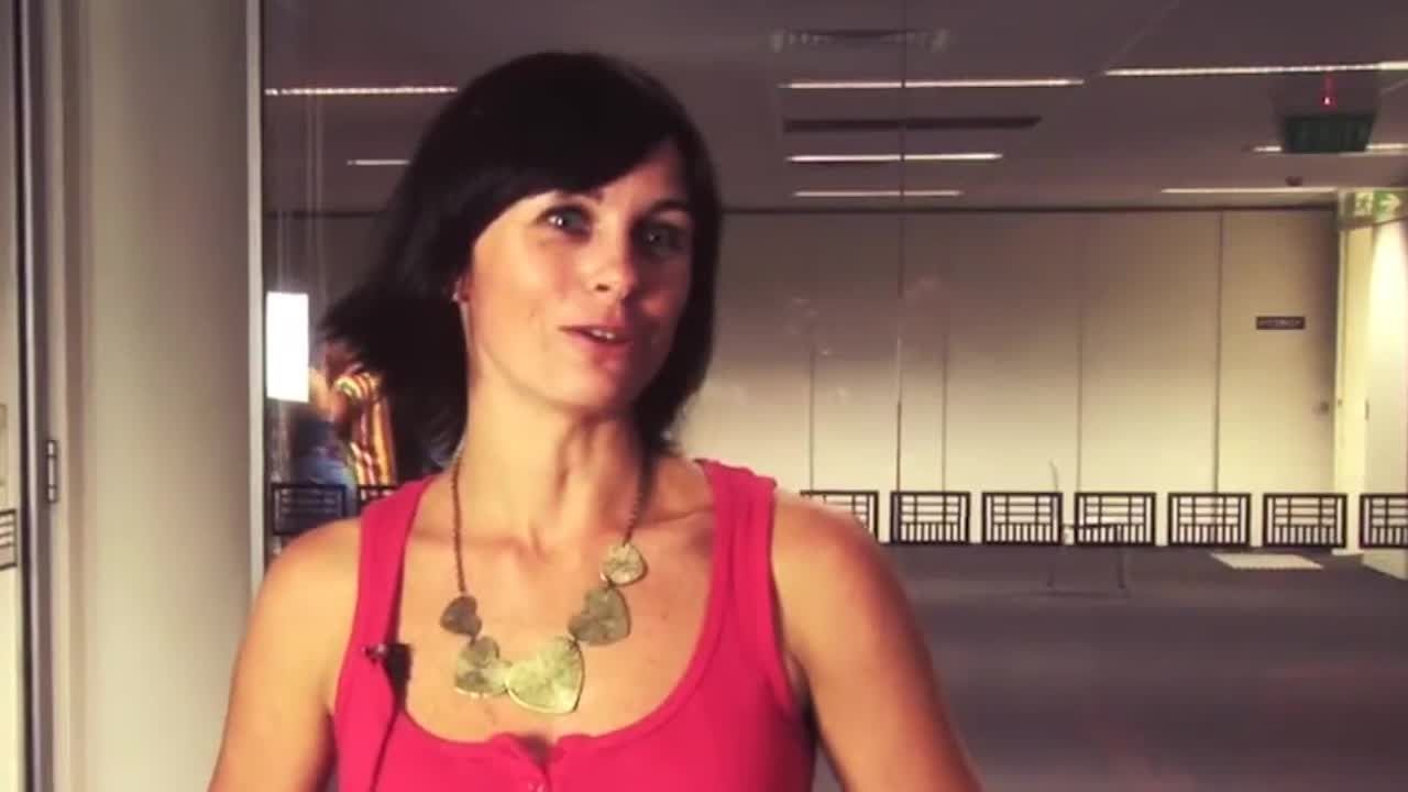 Women with a short black hair wearing a pink sleeveless top and a heart shaped gold necklace