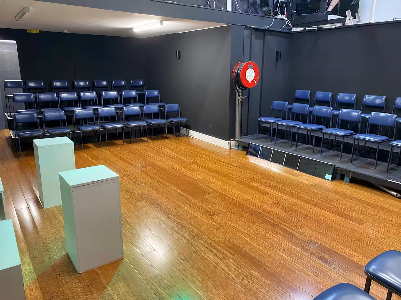 A spacious room with chairs and a stage set up for performances or presentations. Darlinghurst Venue hire