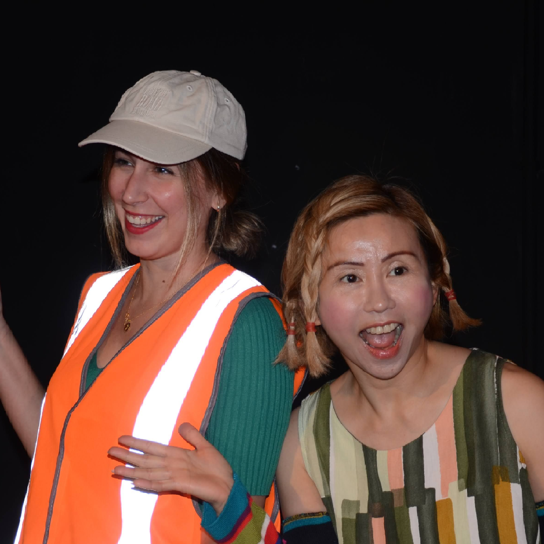 Male and female standing in front of dark background while holding hands