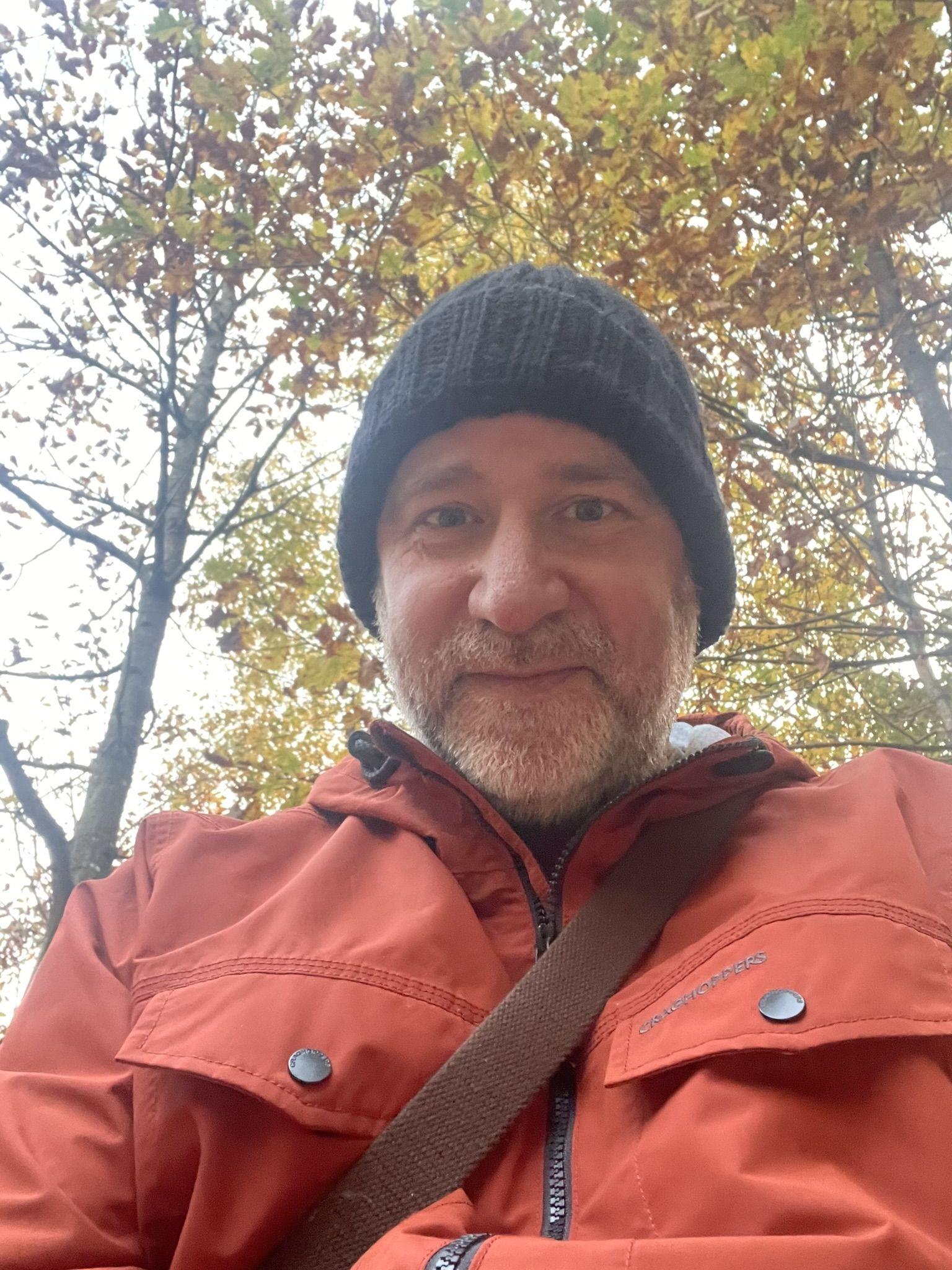 Alex McGuinness, a neurodiversity coach in the UK, sitting in a calm and welcoming space with a framed artwork behind him.