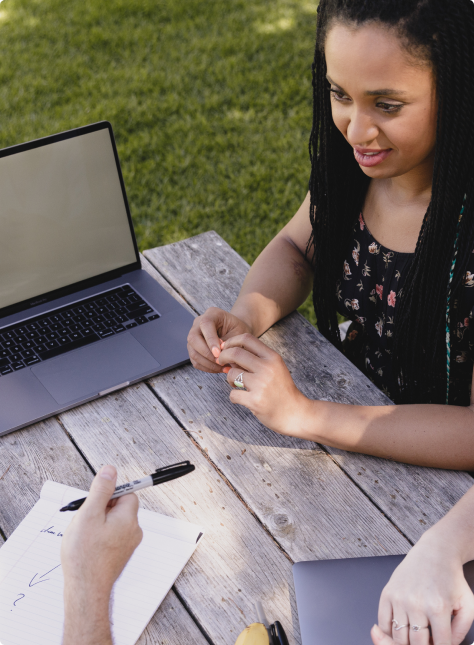 A woman sitting at a bench with a laptop.