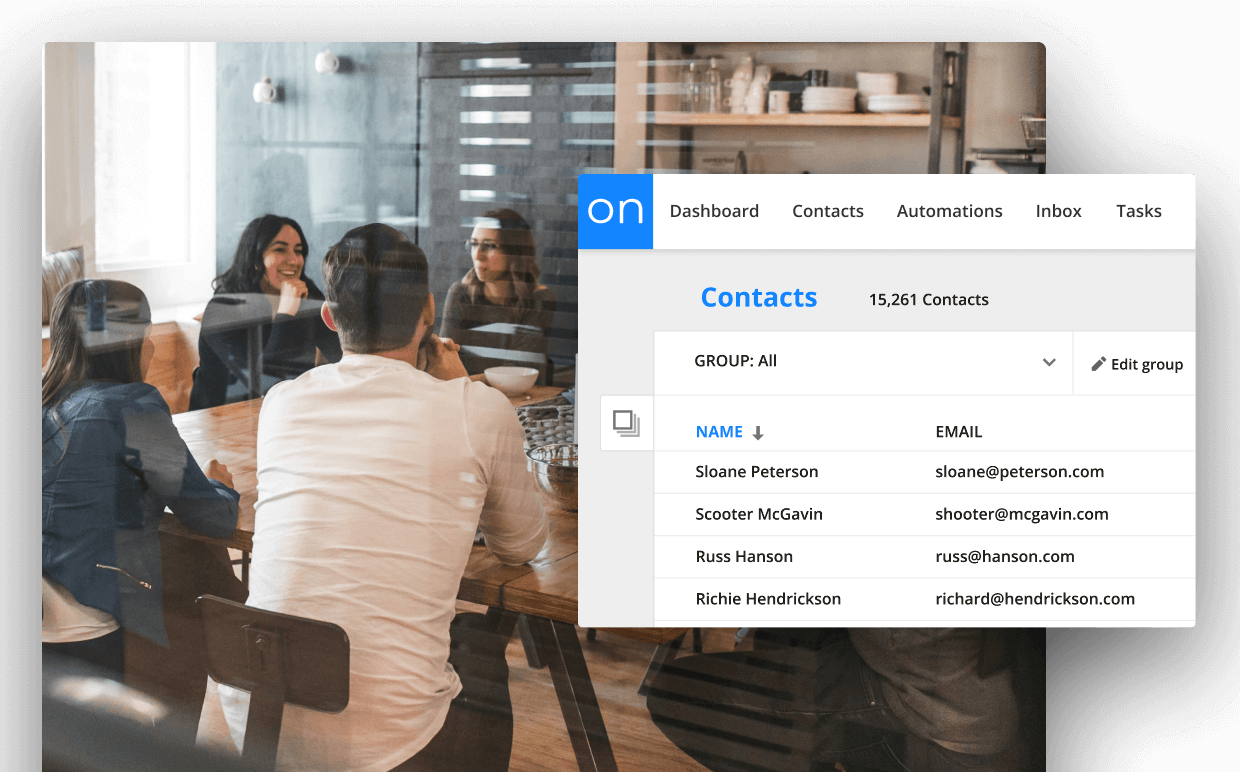Two people sitting at a desk in a meeting with an image of Ontraport's contact card view. 
