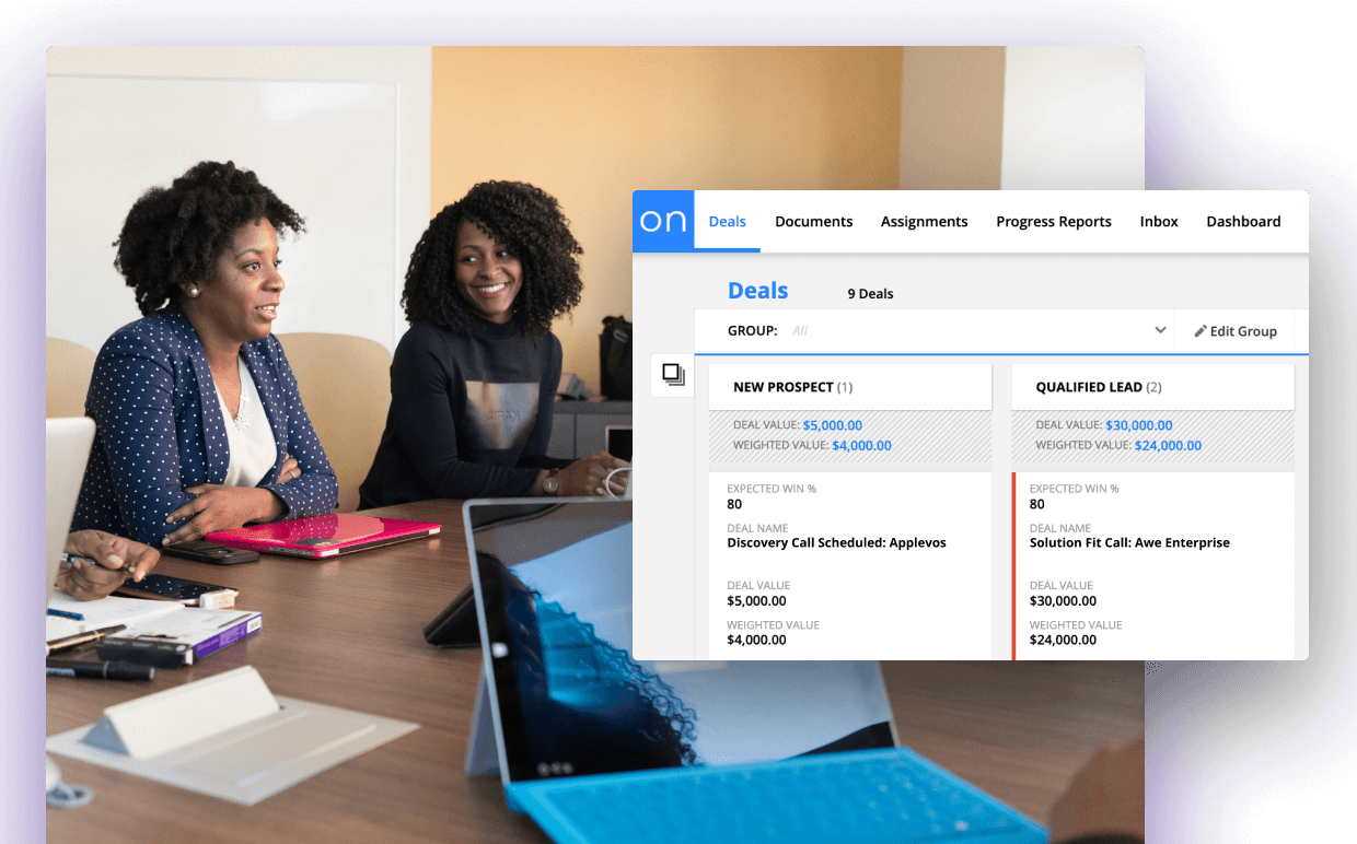 Two people sitting at a desk in a meeting with an image of Ontraport's contact card view. 