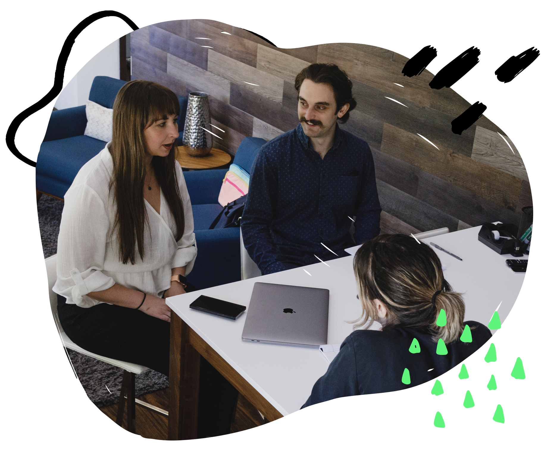 Two females and a male sitting at a table at work laughing.
