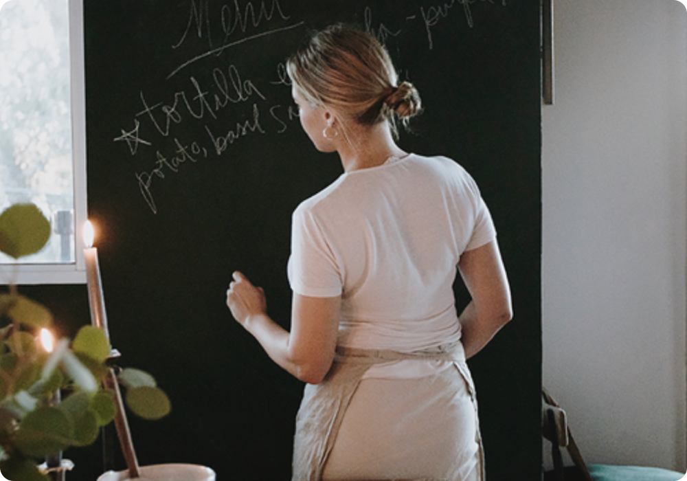 An image of a person writing on a chalkboard